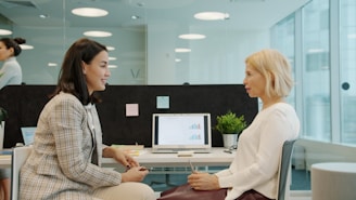 Two women talking in a modern office setting.