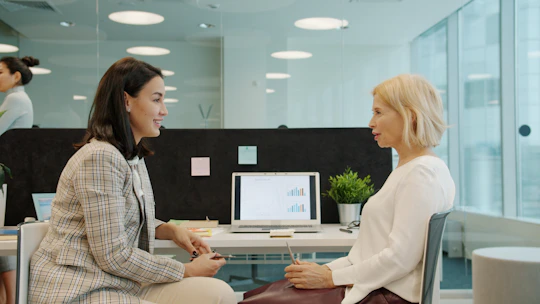 Two women talking in a modern office setting