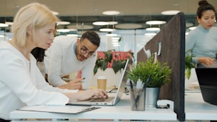 Colleagues collaborating on a project at office desks.