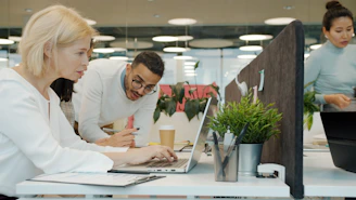 Colleagues collaborating on a project at office desks.