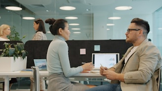 Two colleagues discussing work at their desks.