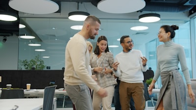 Quatre collègues debout en conversation et riant dans un bureau en open space