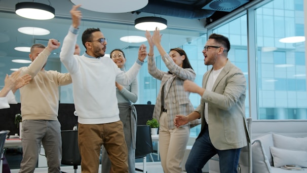A diverse group of colleagues celebrating success in an office.