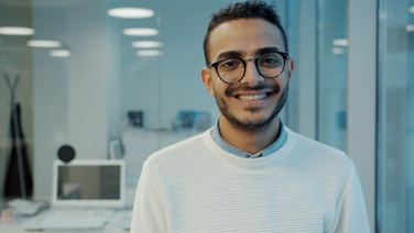 A smiling man wearing glasses in an office setting.