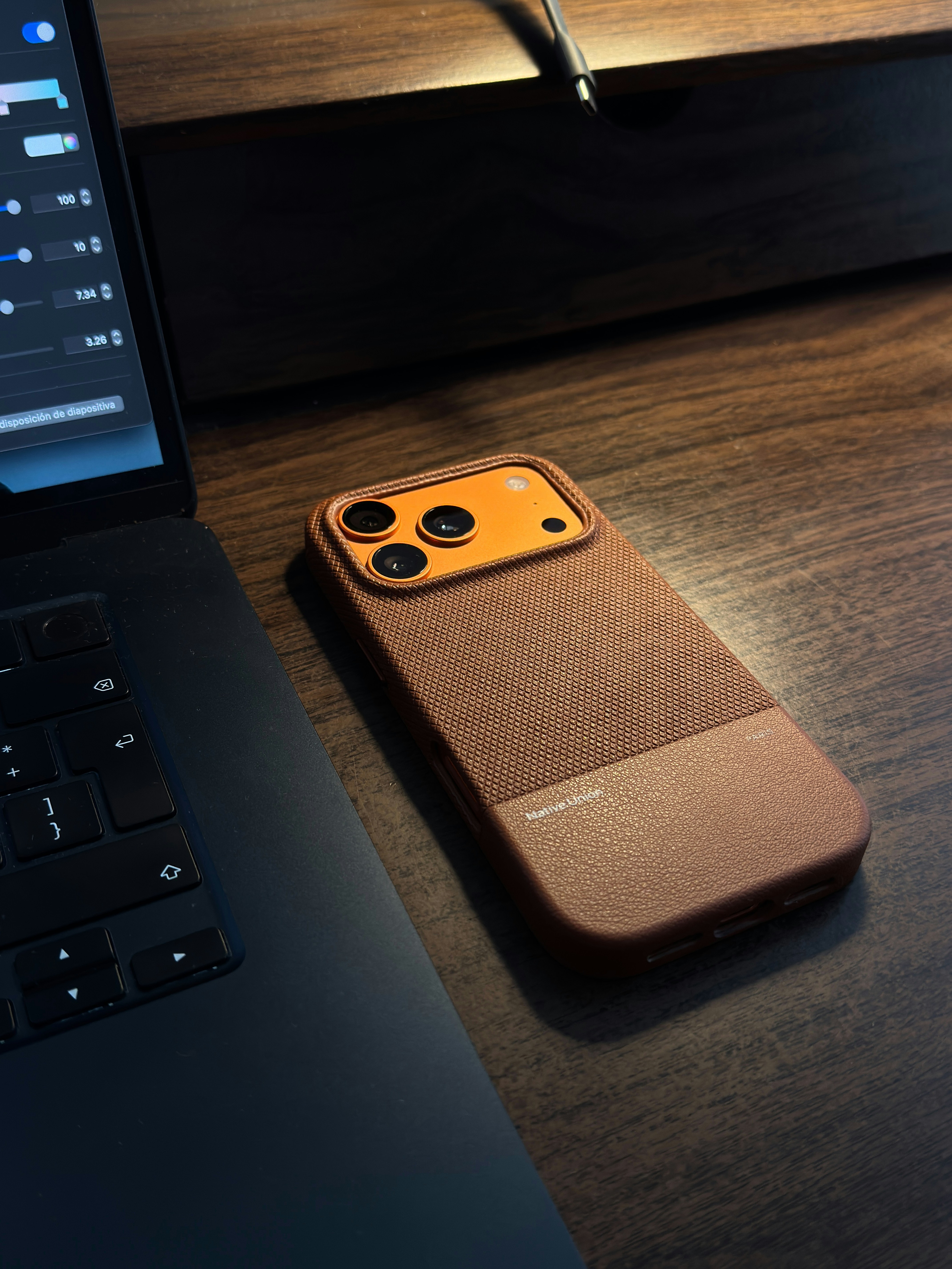 Smartphone with brown case next to laptop on desk