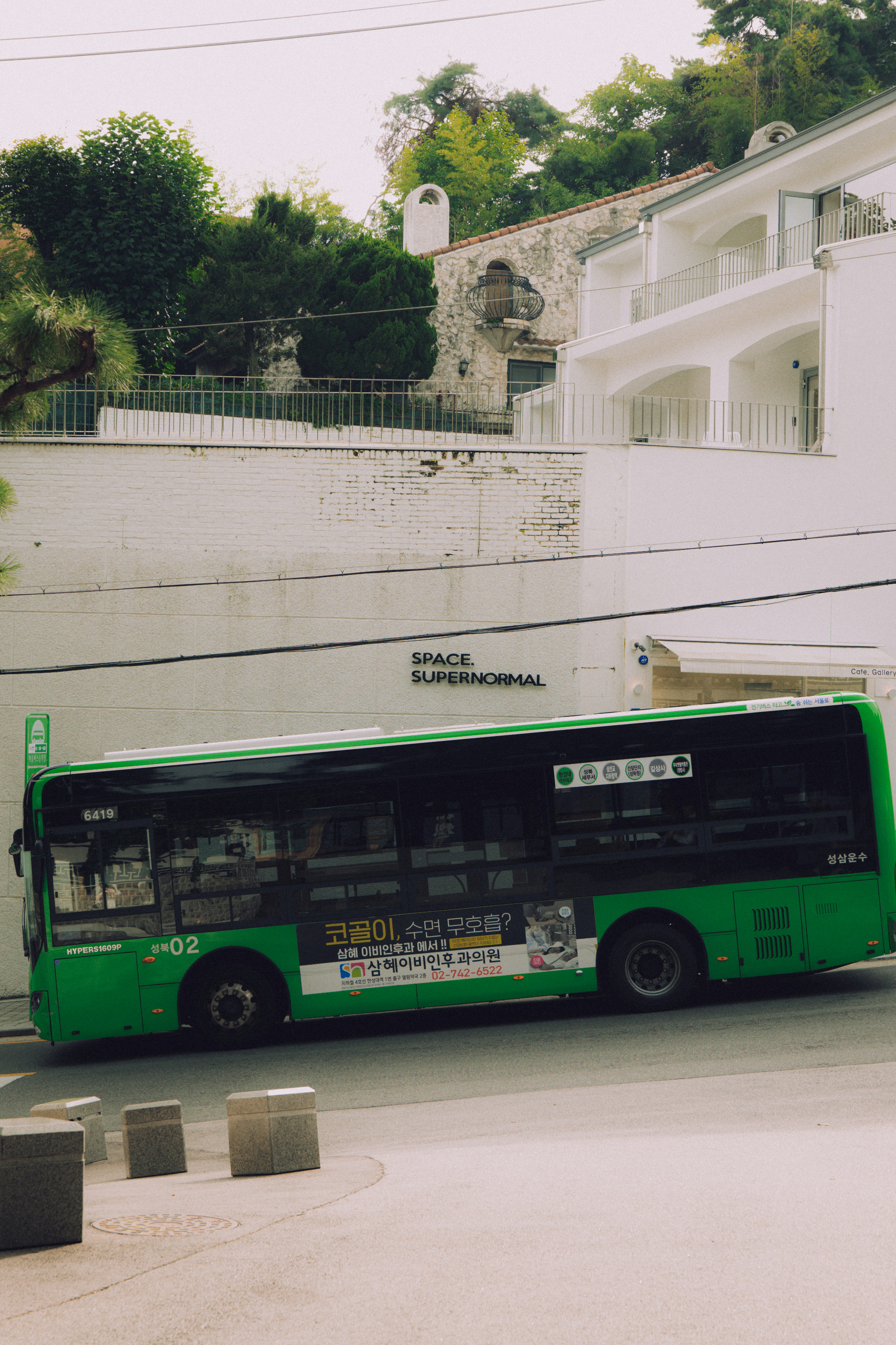 A green bus parked on a street with buildings.