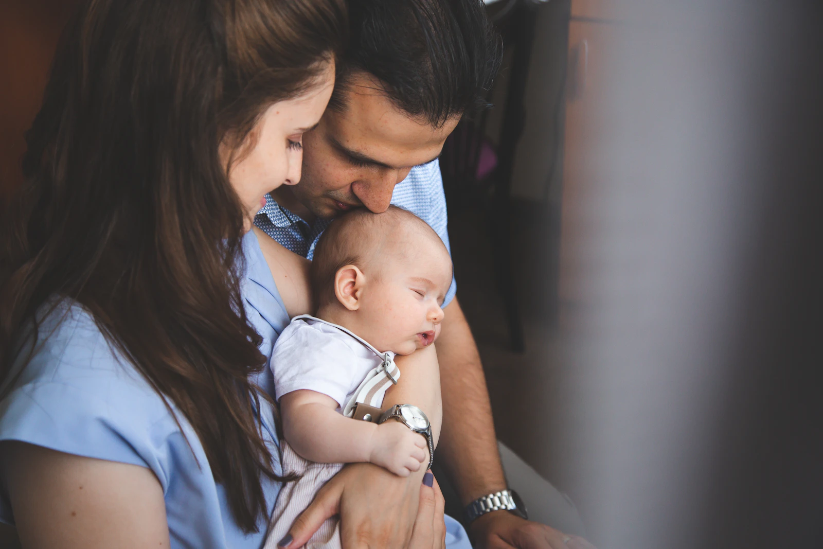 Deux parents blottis autour de leur nouveau-né endormi dans les bras