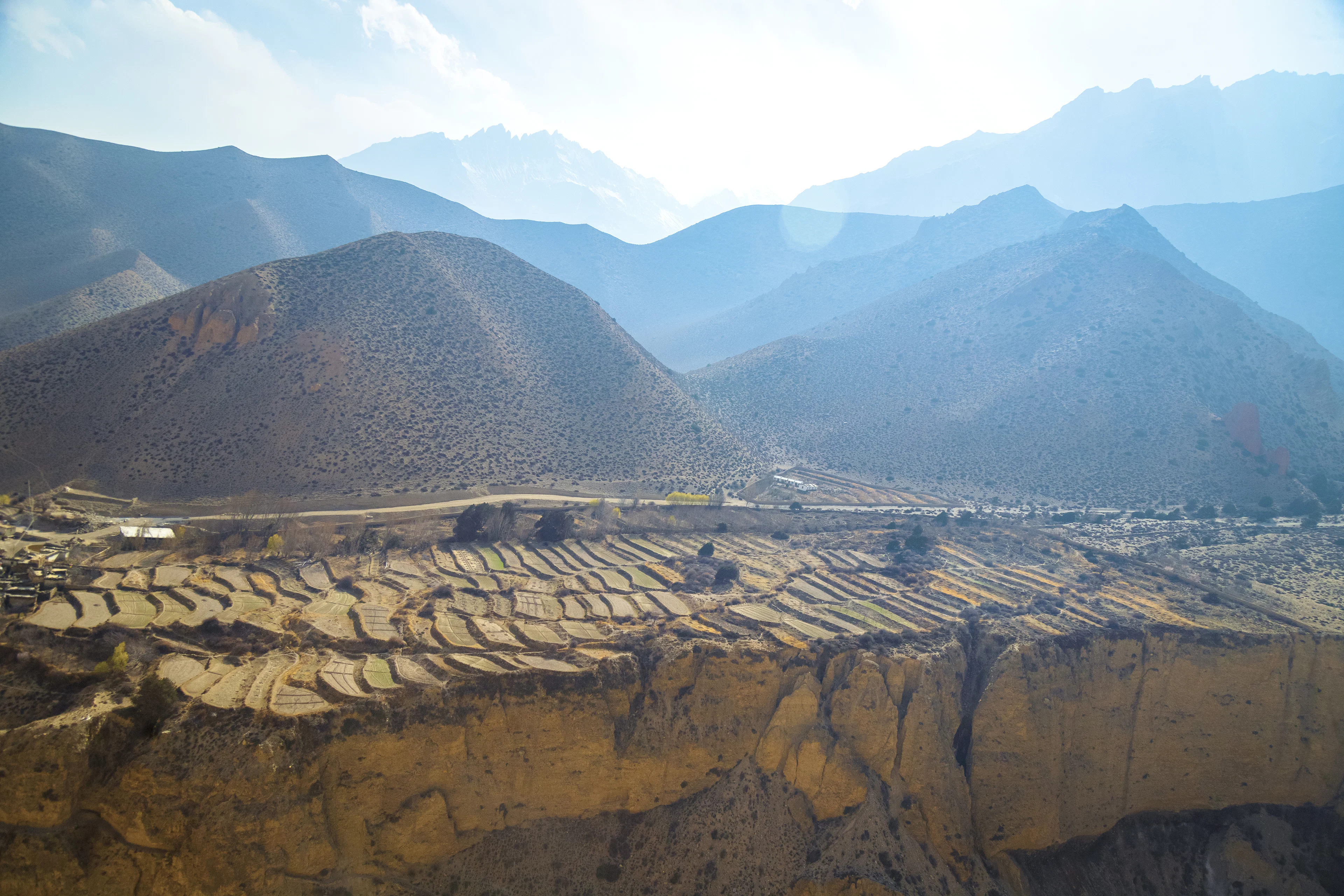 Terraced fields on a cliffside with mountains beyond