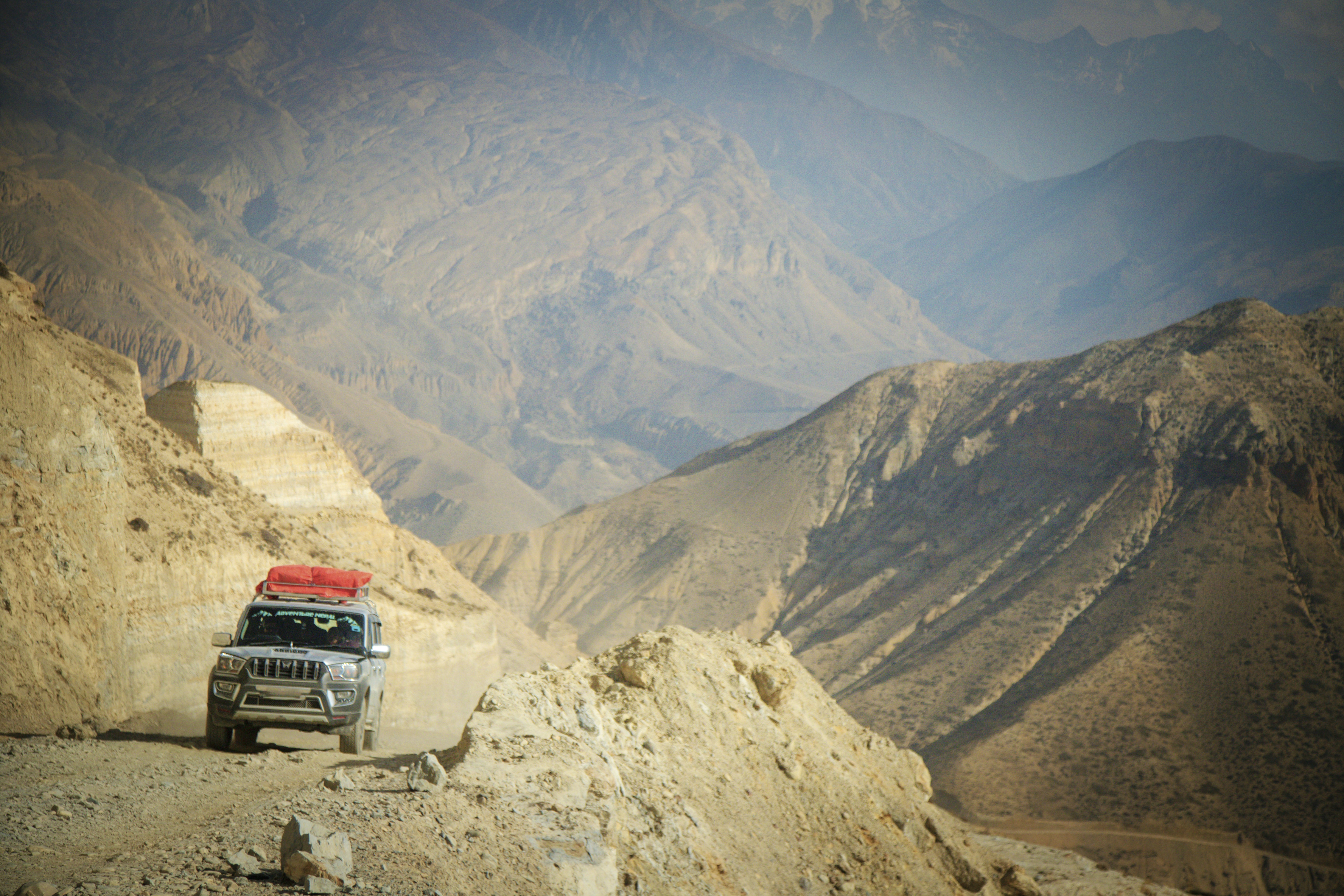 A jeep drives on a mountain road with scenic views.