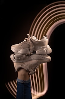 A hand holds a sneaker over its reflection