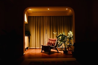 Cozy armchair with plants in a dimly lit room.