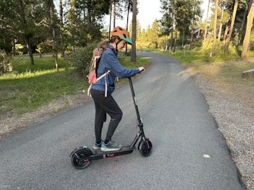Person riding an electric scooter on a paved path.