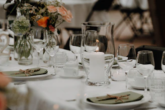 A decorated table setting with a lit candle and flowers.