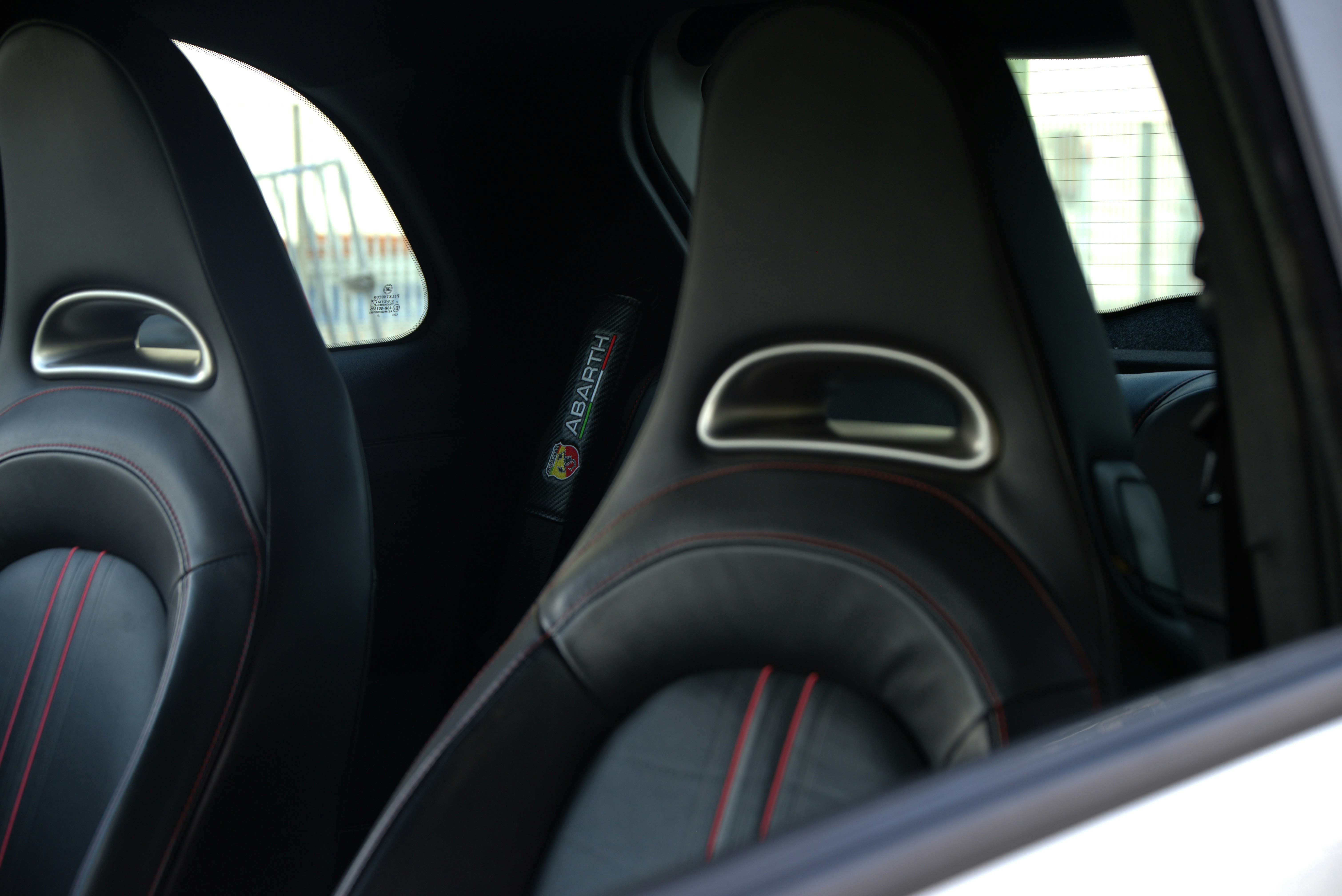 Two black leather car seats with red stitching