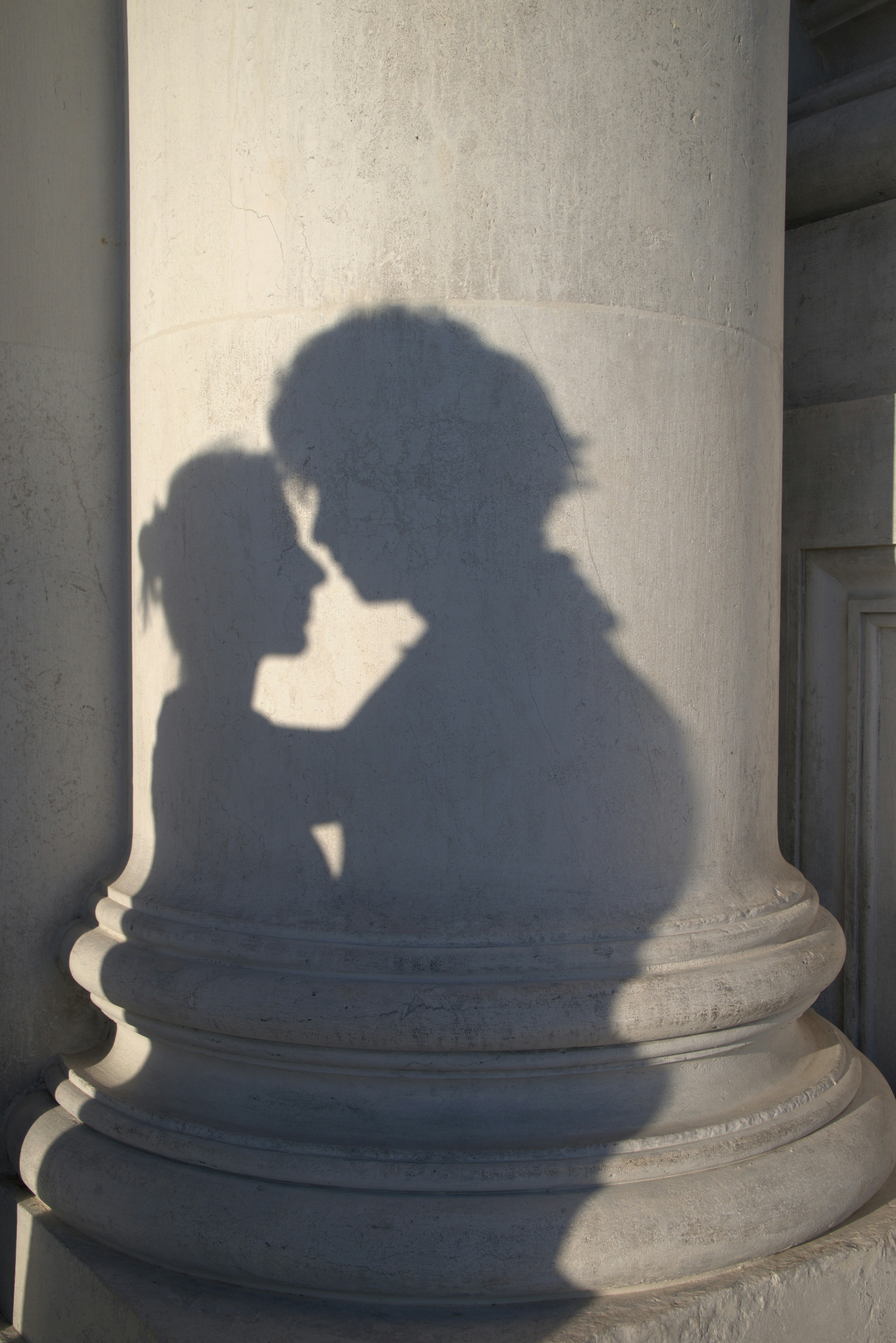 Shadows of a couple embracing on a column.