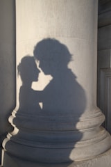 Shadows of a couple embracing on a column.