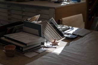 Desk with books, papers, and calculator in-tray