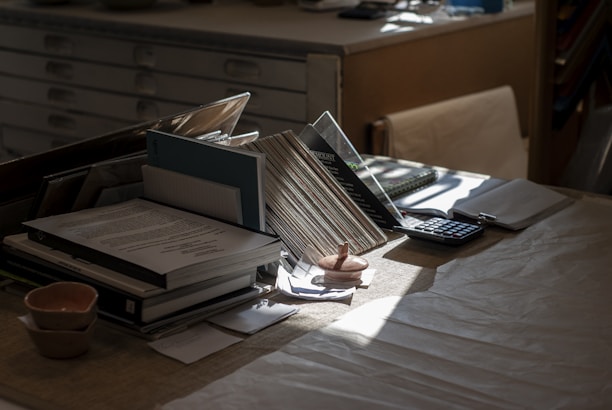 Desk with books, papers, and calculator in-tray