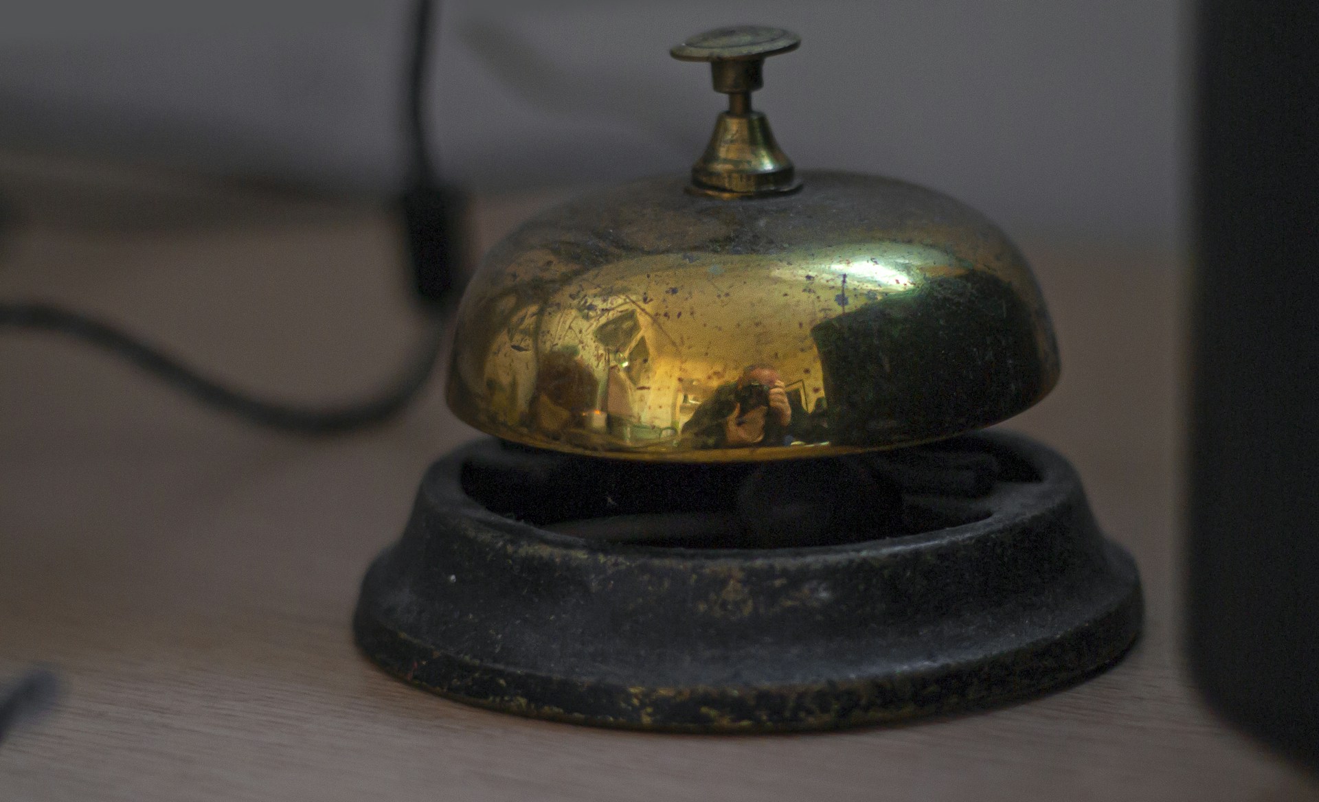 A vintage brass service bell on a wooden desk.