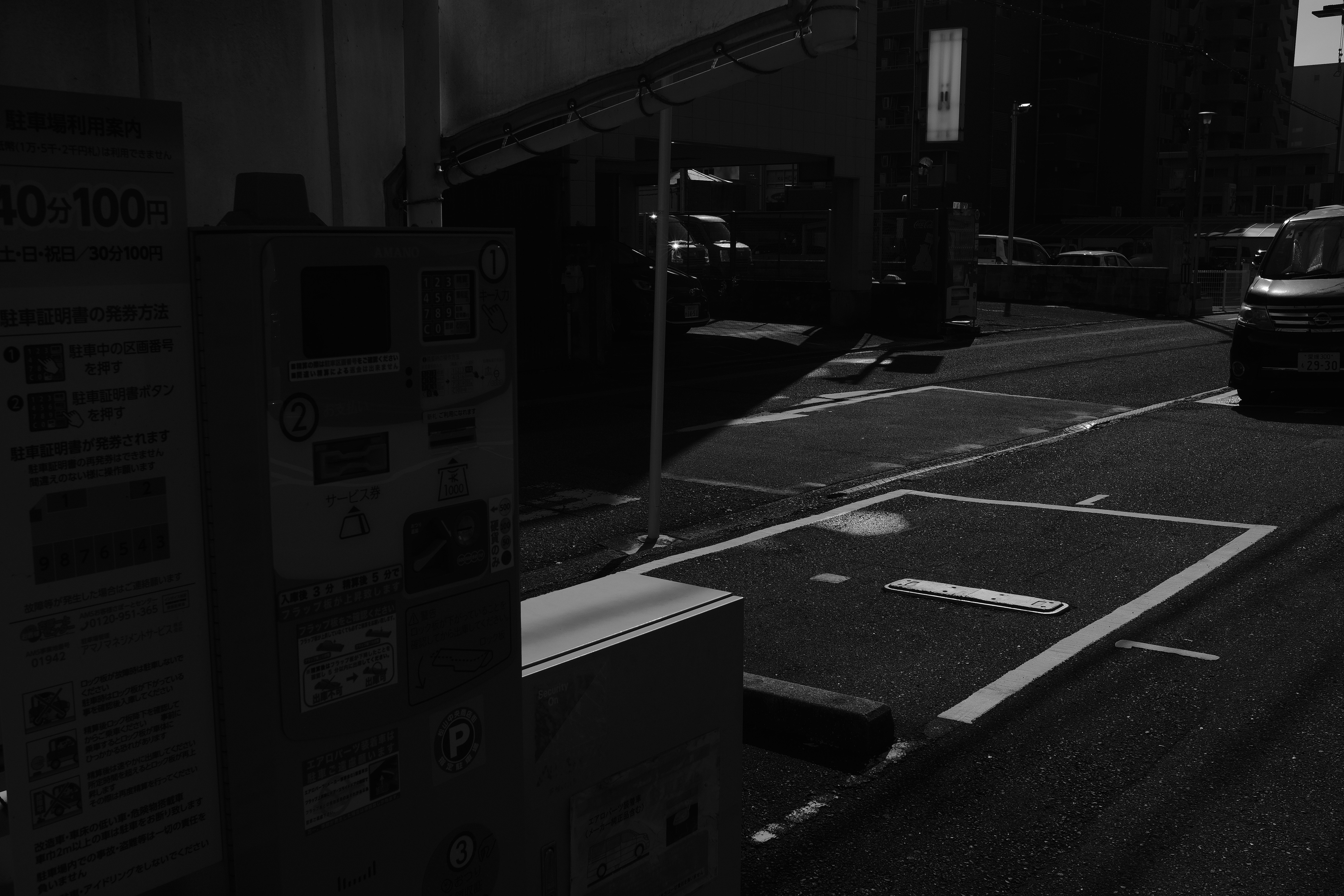 Dark street scene with parking spaces and machine.