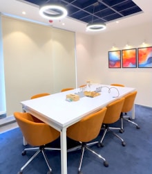 Modern conference room with orange chairs and artwork.