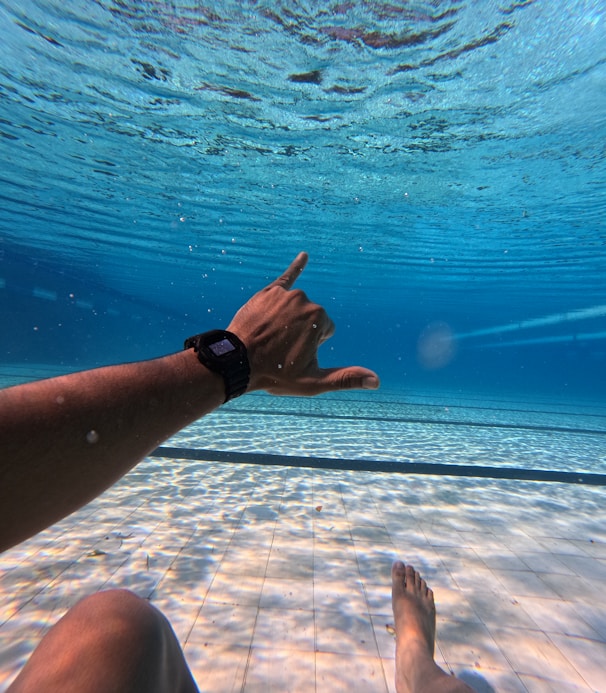 Underwater view of a person signaling shaka sign