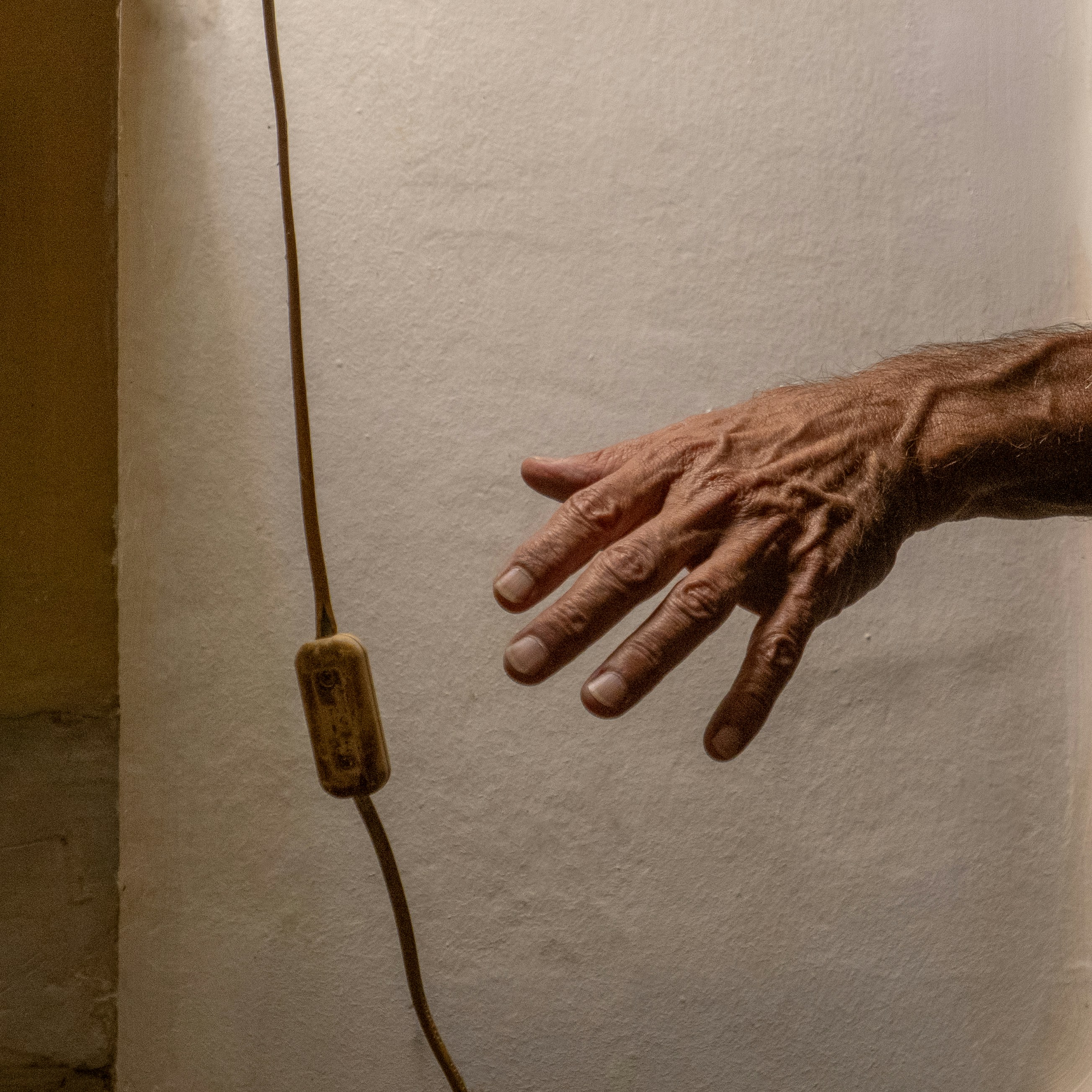Elderly hand reaching for light switch on wall