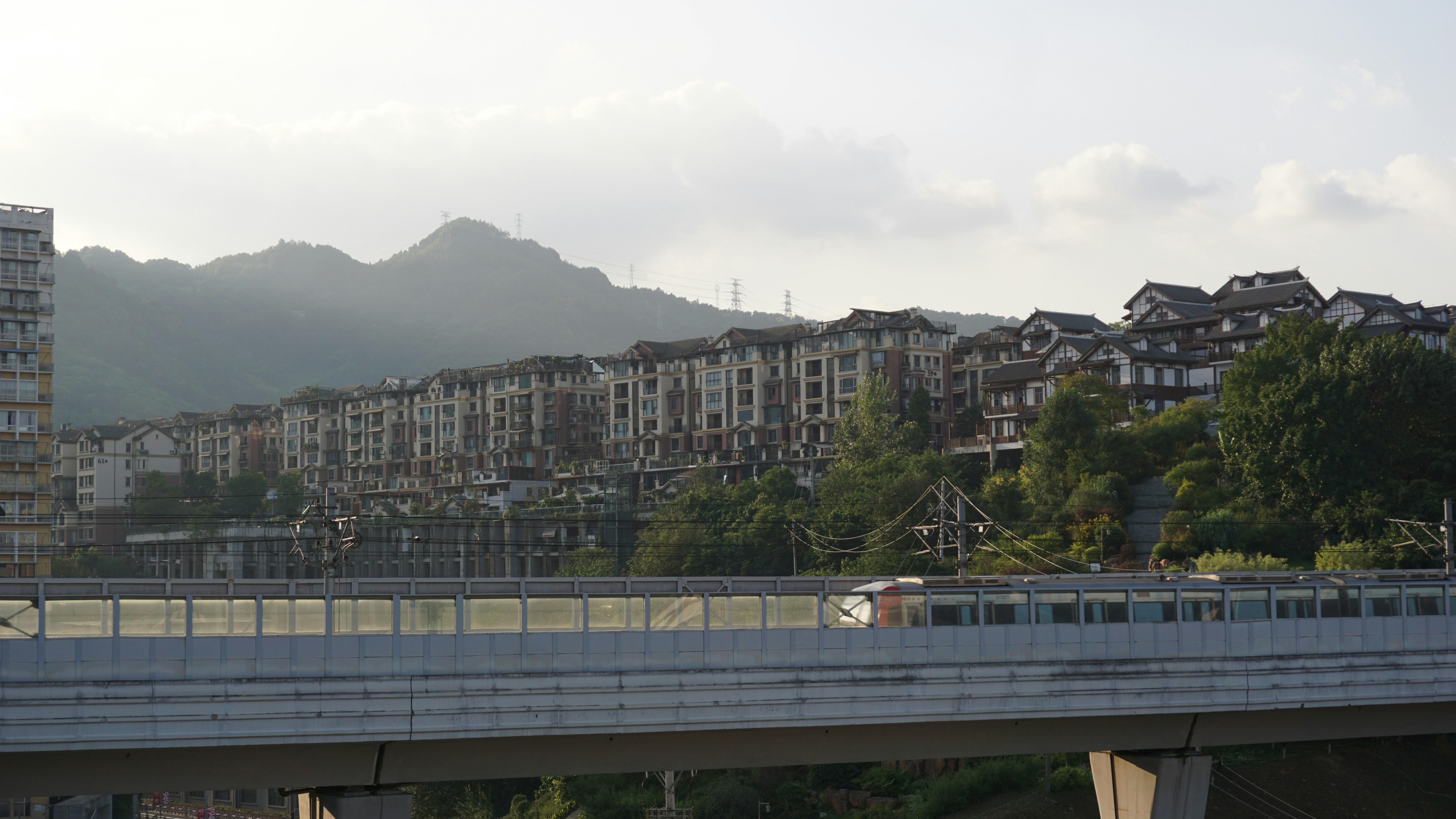 Los edificios de apartamentos se alinean en una ladera con un tren que pasa.