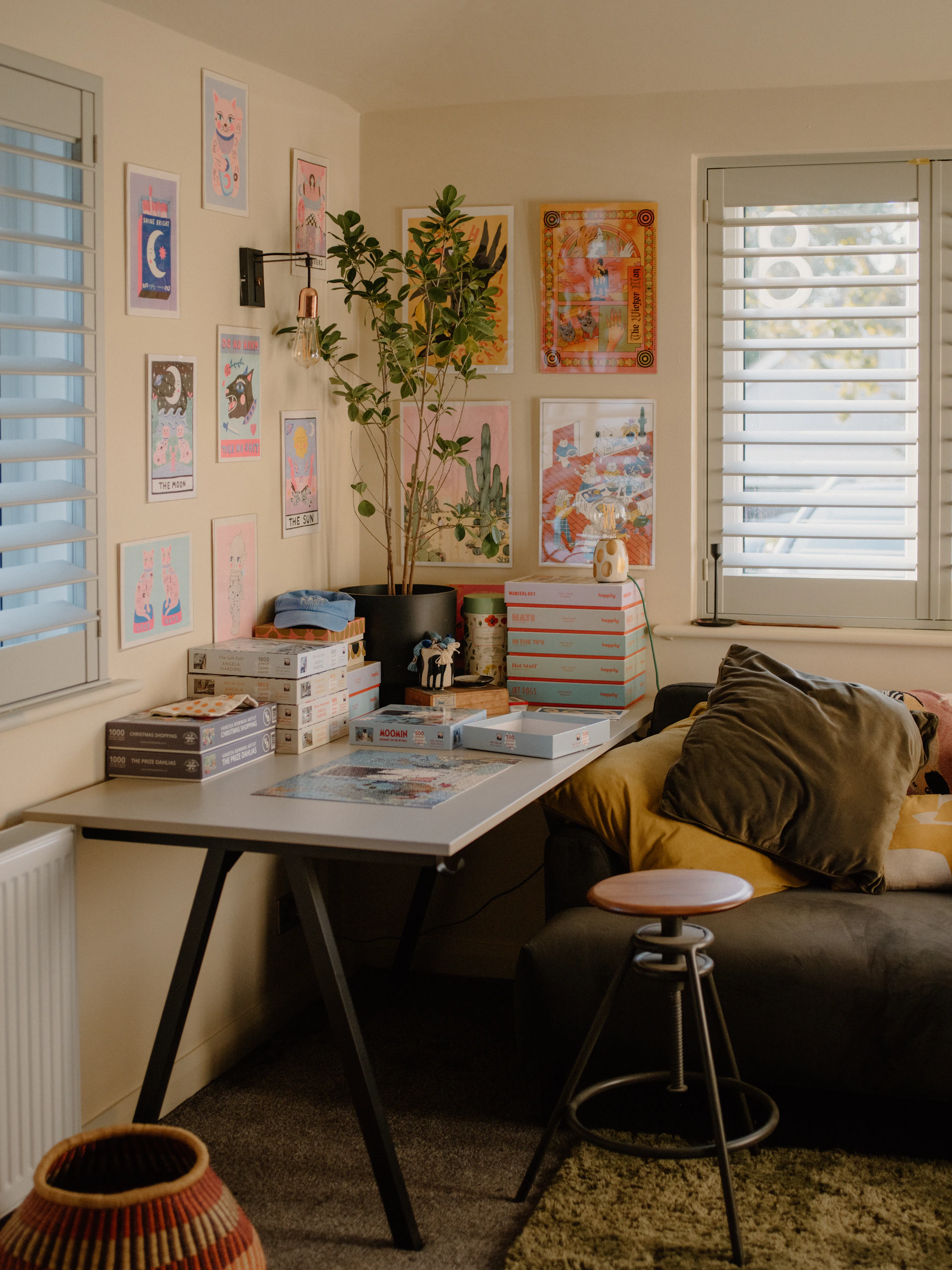 Desk with artwork and plants next to a sofa.
