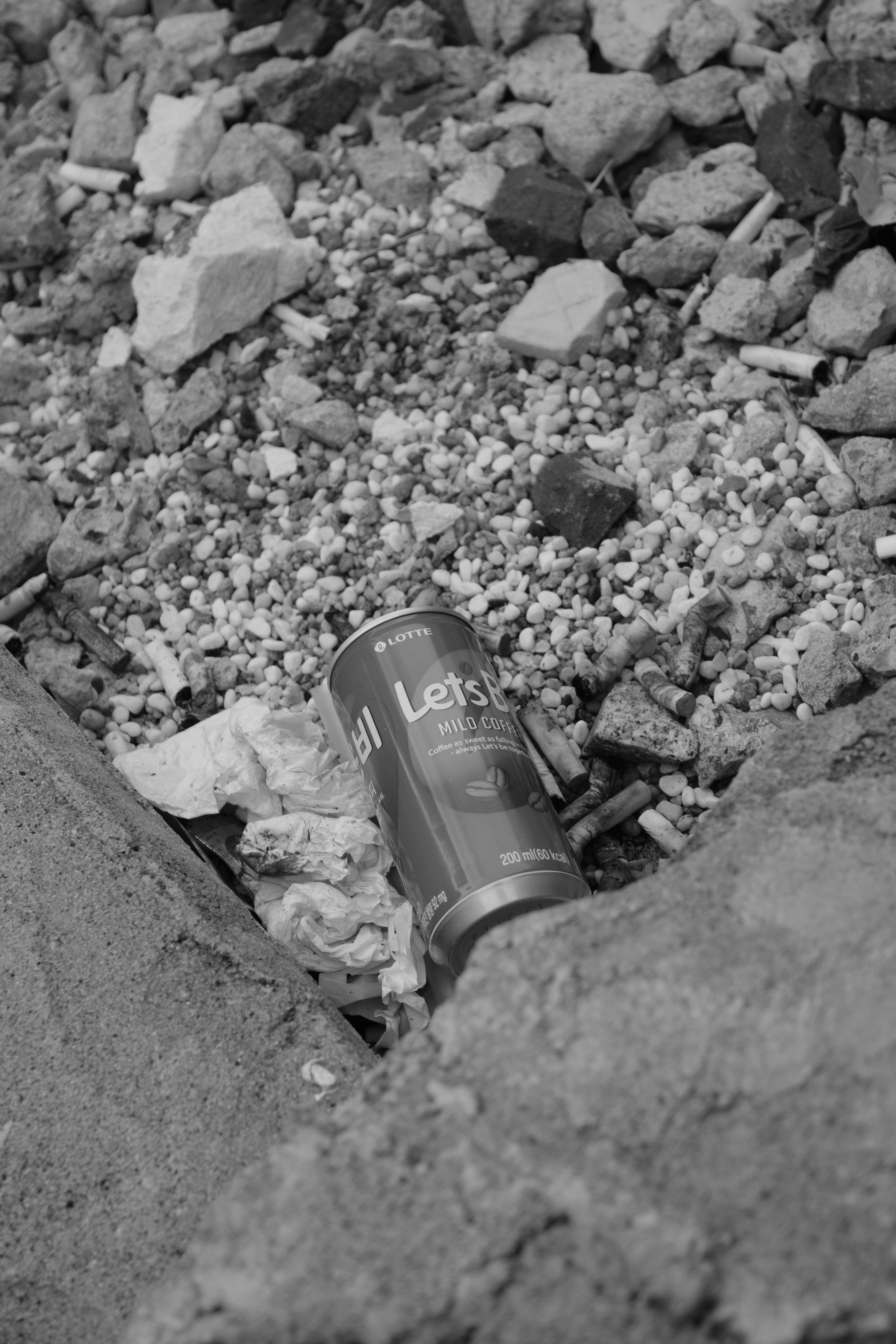 A discarded soda can lies amongst rubble and debris.