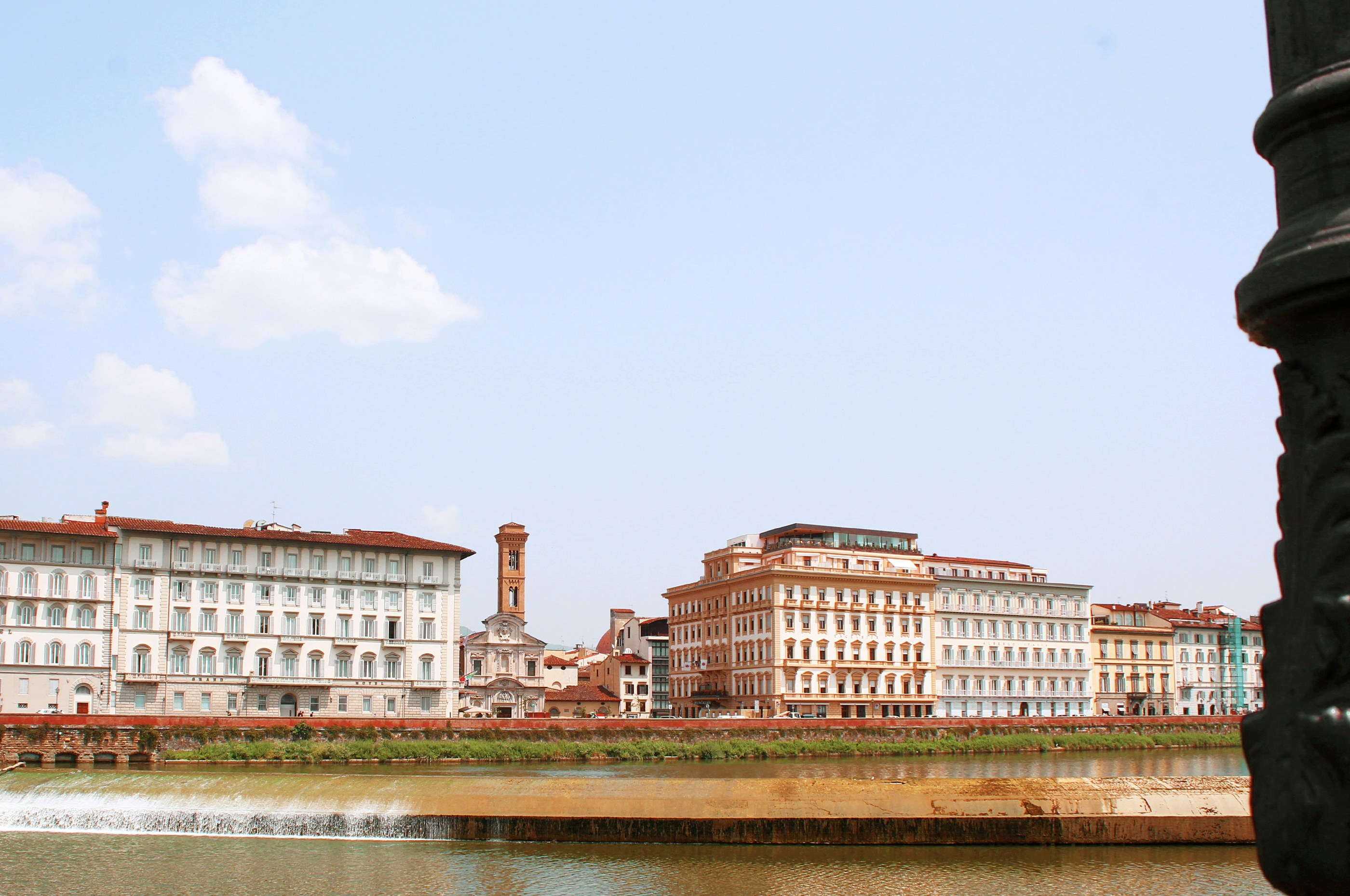 Buildings line a river with a bell tower.