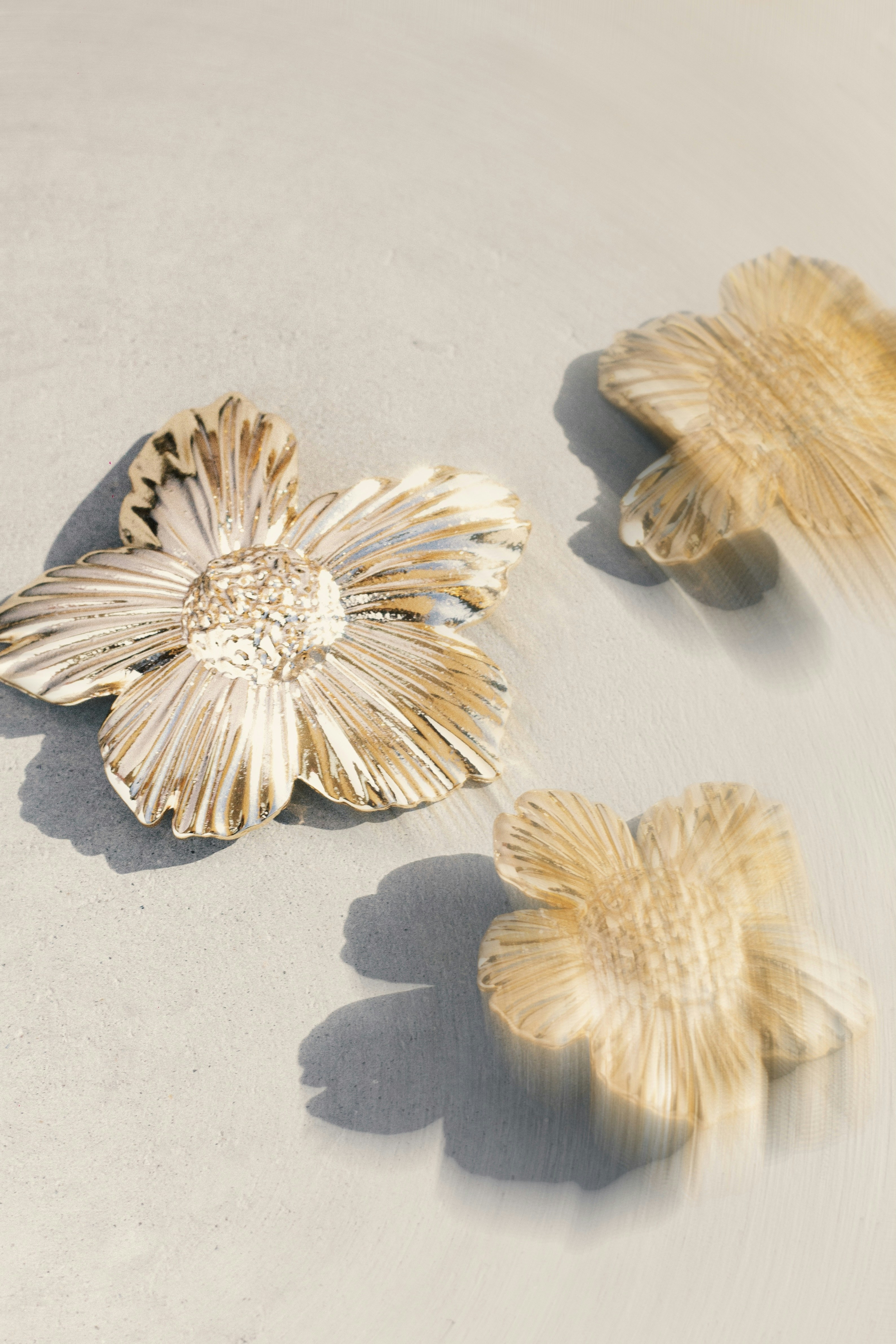 Three golden flowers on a light gray surface.