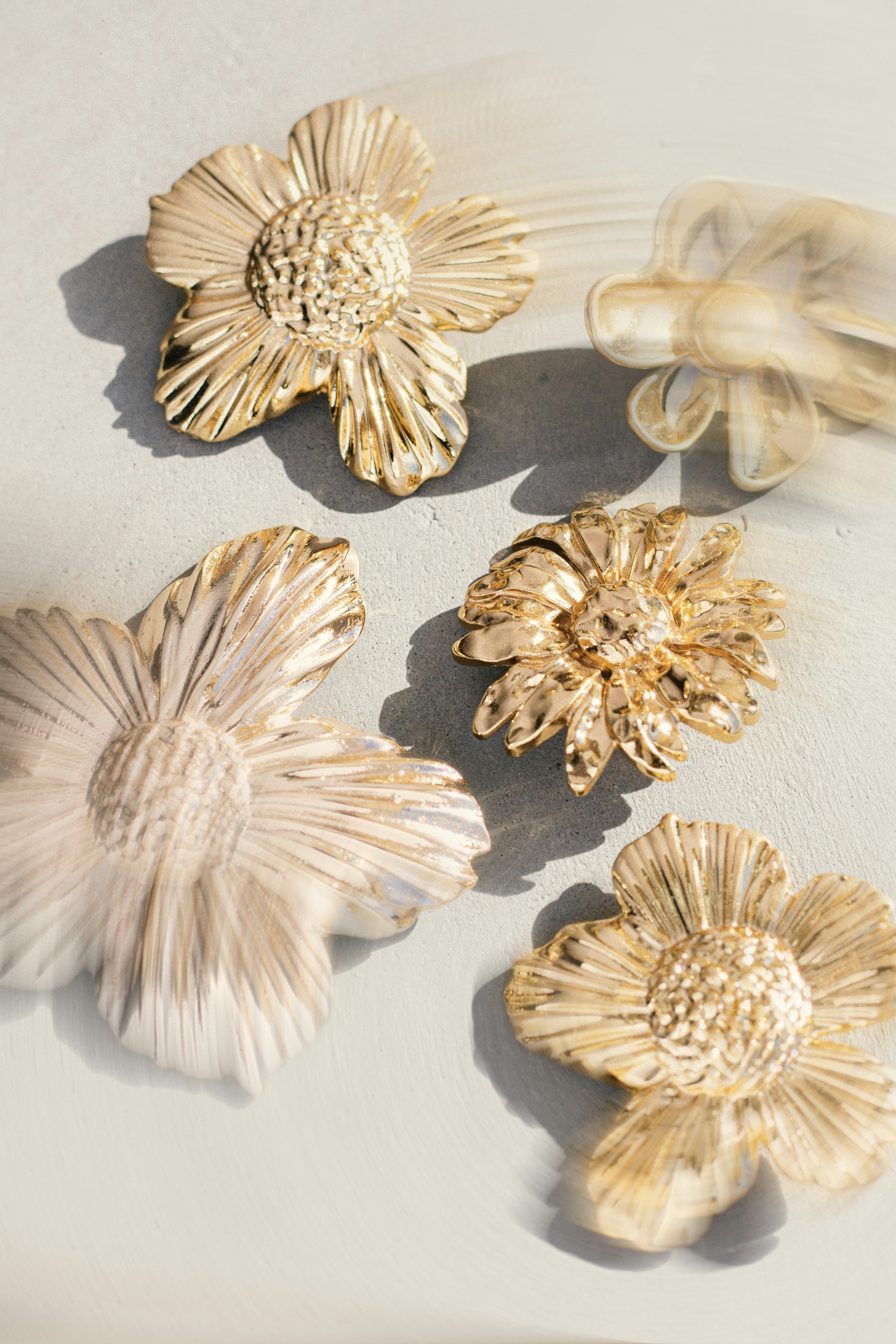 Five golden floral decorative objects on a light surface.
