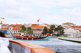 Traditional boat sailing on canal with buildings.