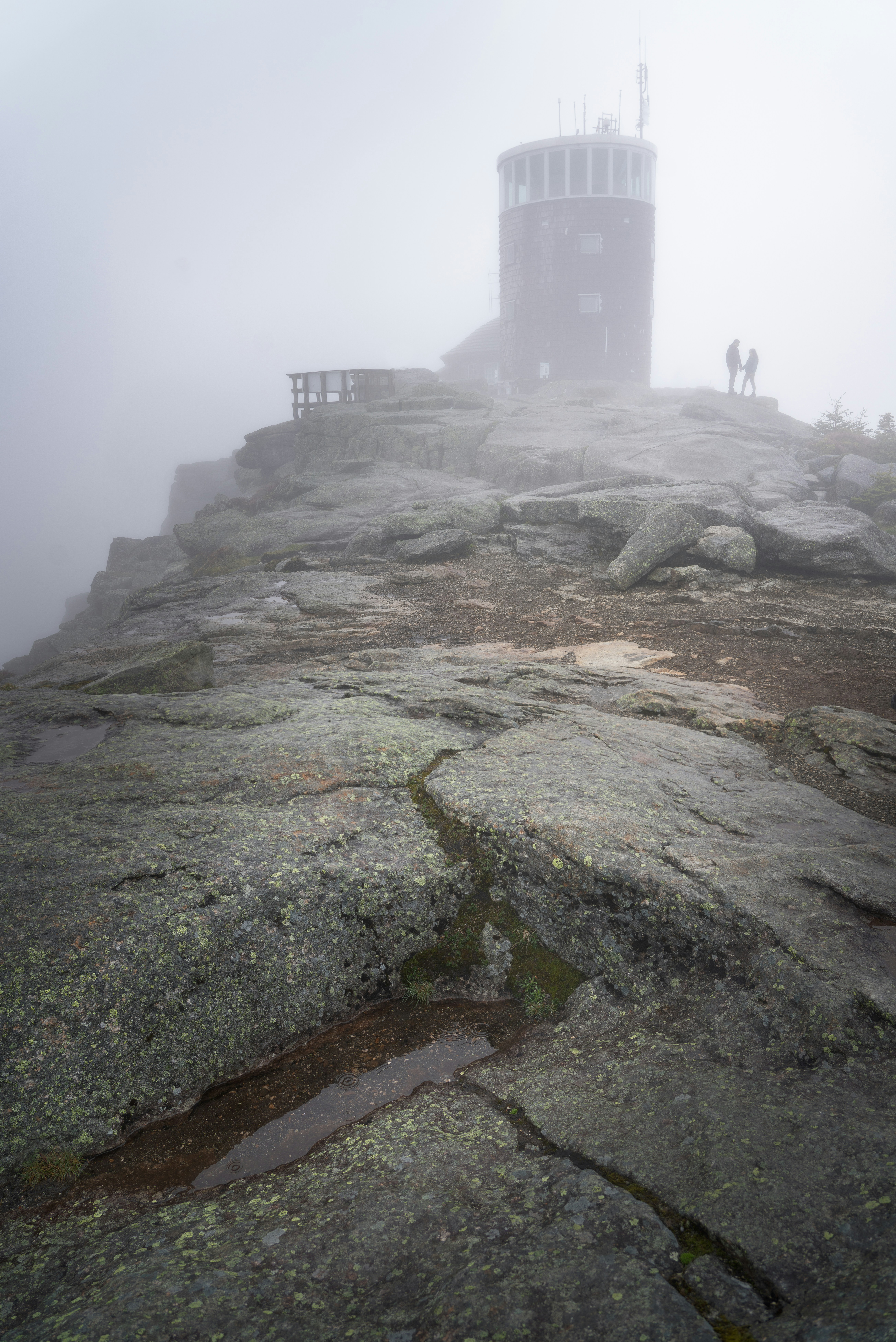 Misty mountain peak with observation tower and two people