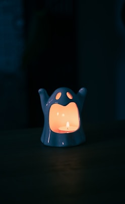 A ghost-shaped lantern with a lit candle inside.
