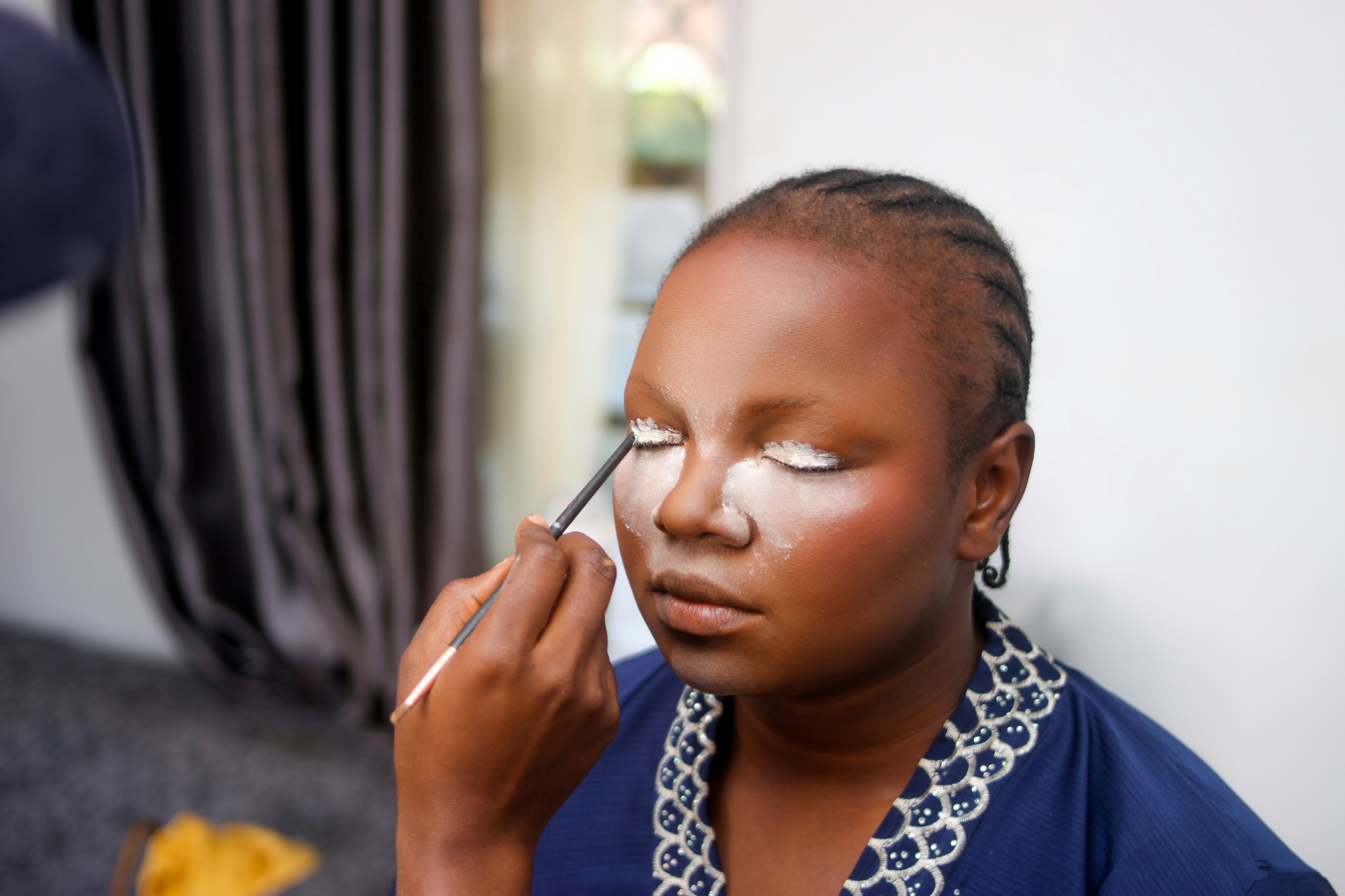 Makeup artist applying eyeshadow to a woman's eyes.