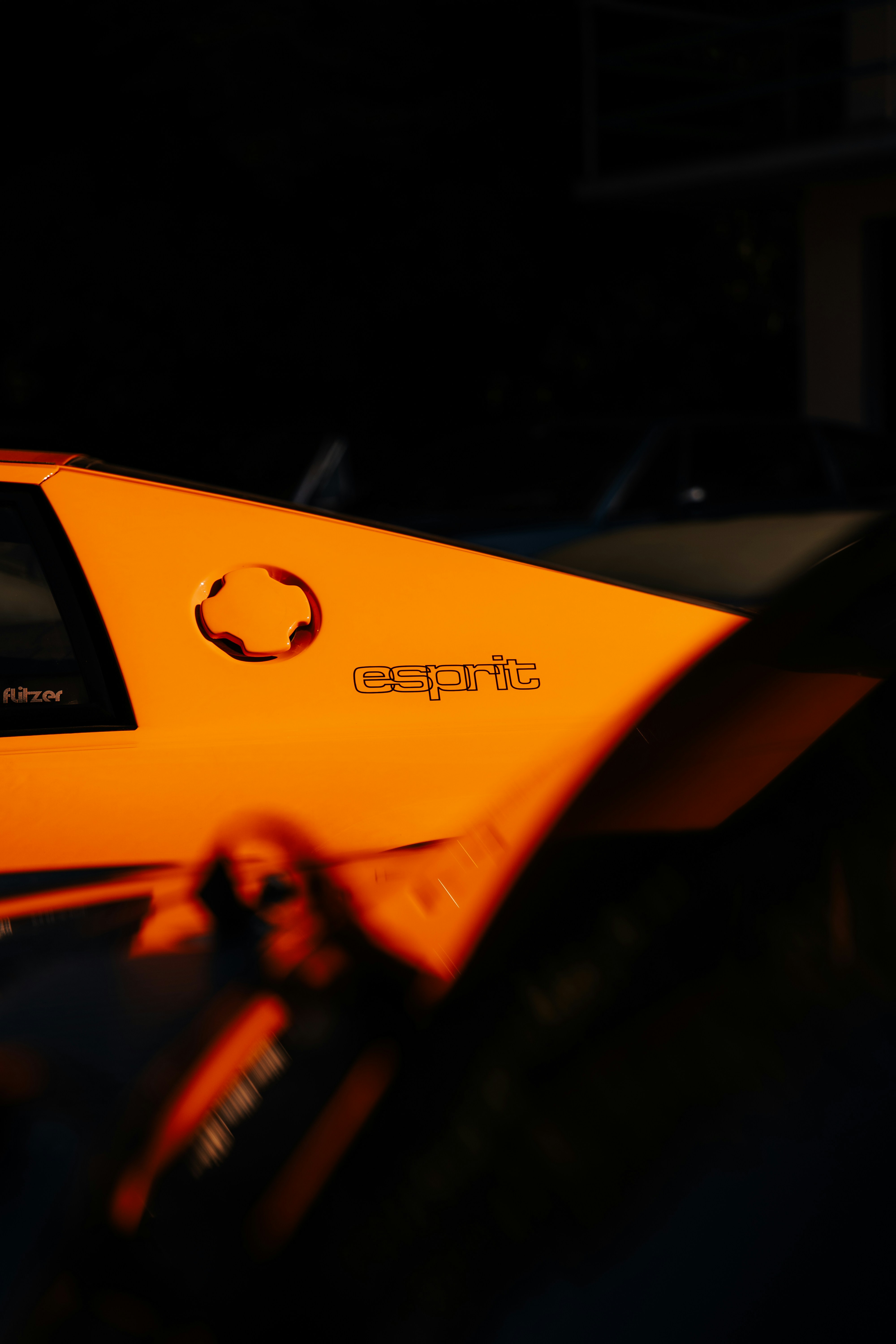 Orangefarbenes Auto mit "Esprit"-Logo in der Dunkelheit
