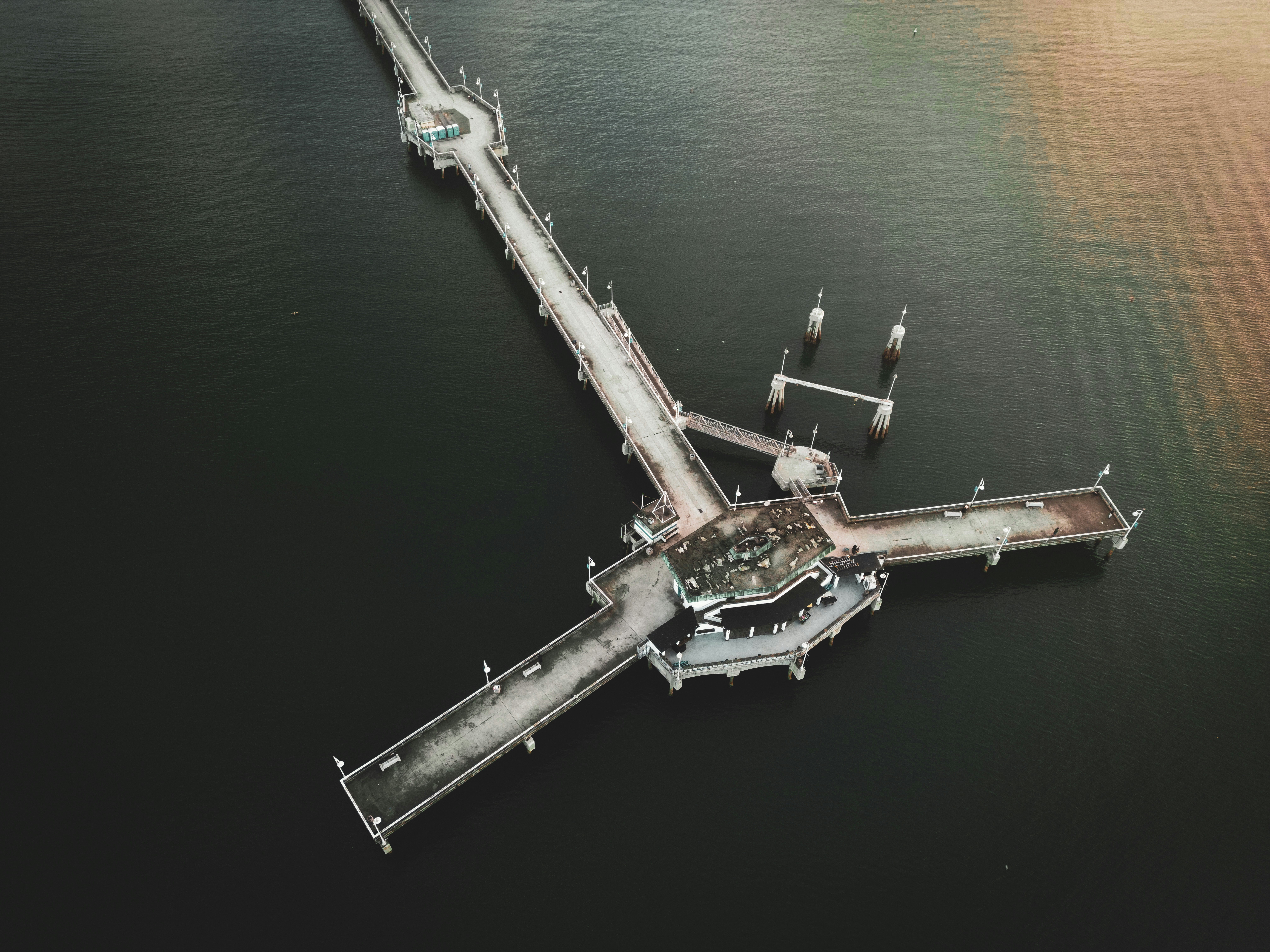 Luftaufnahme einer Seebrücke, die sich in dunkles Wasser erstreckt