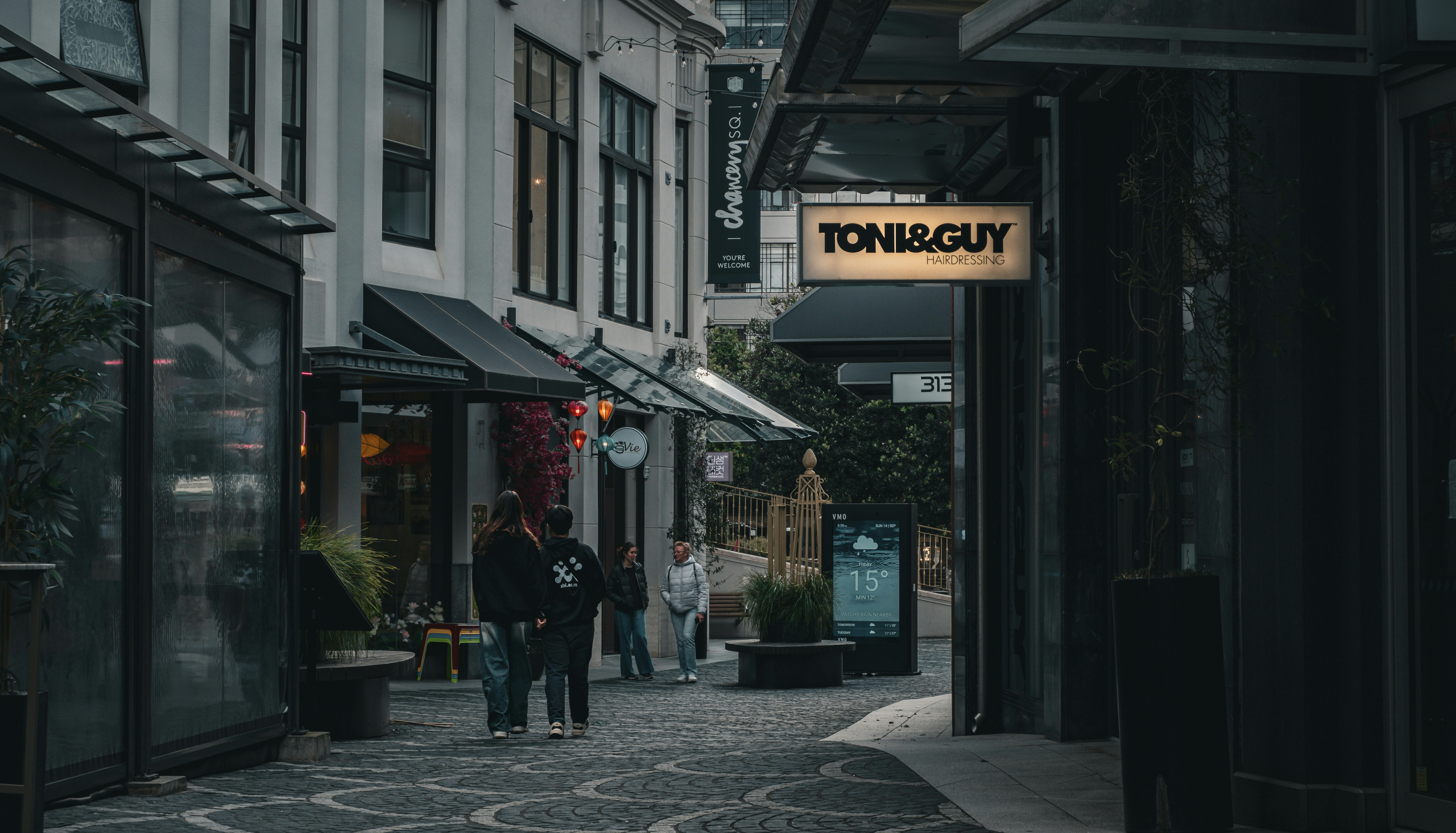 People walking down a cobblestone street with shops.