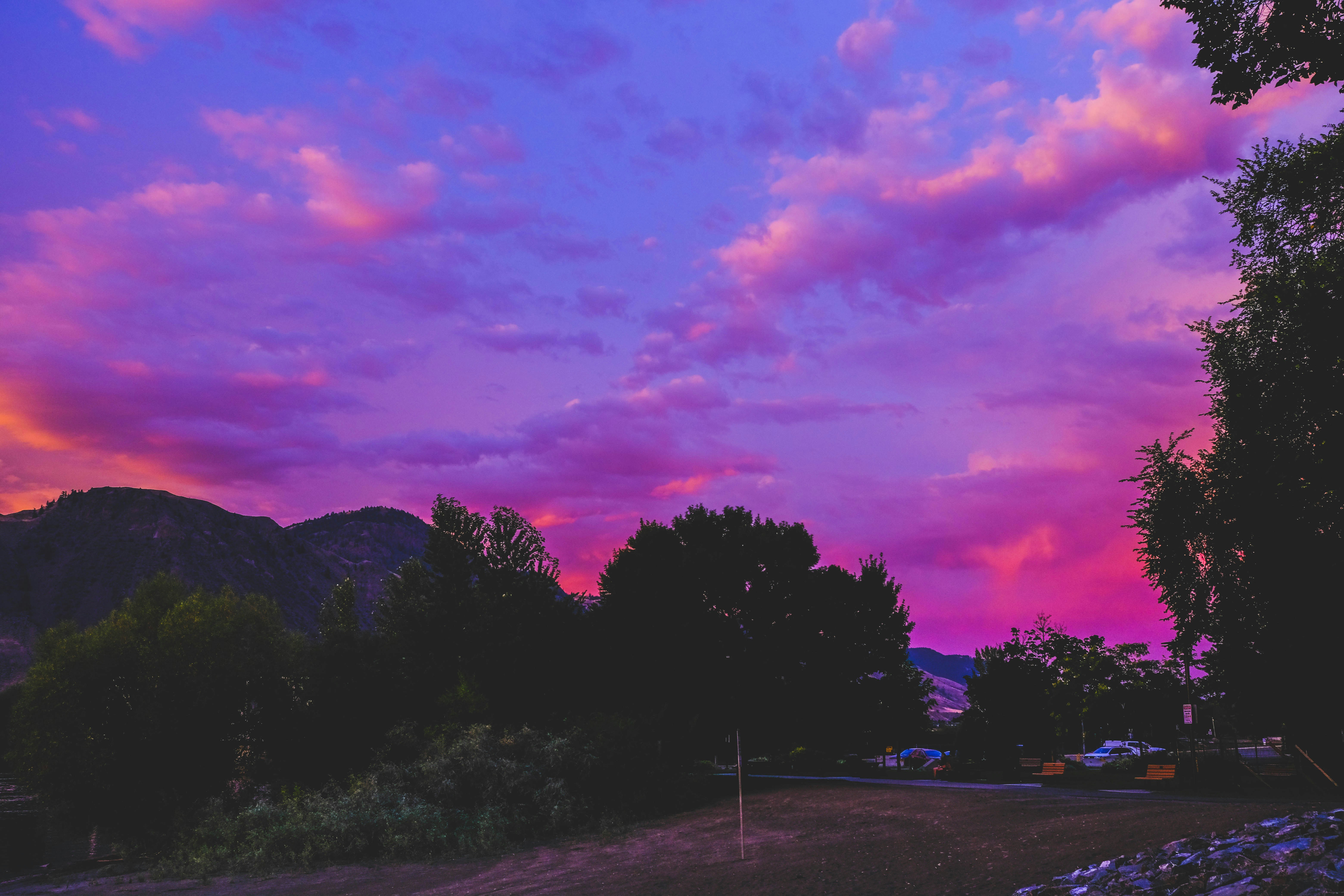 Vibrant purple and pink clouds at sunset over mountains.