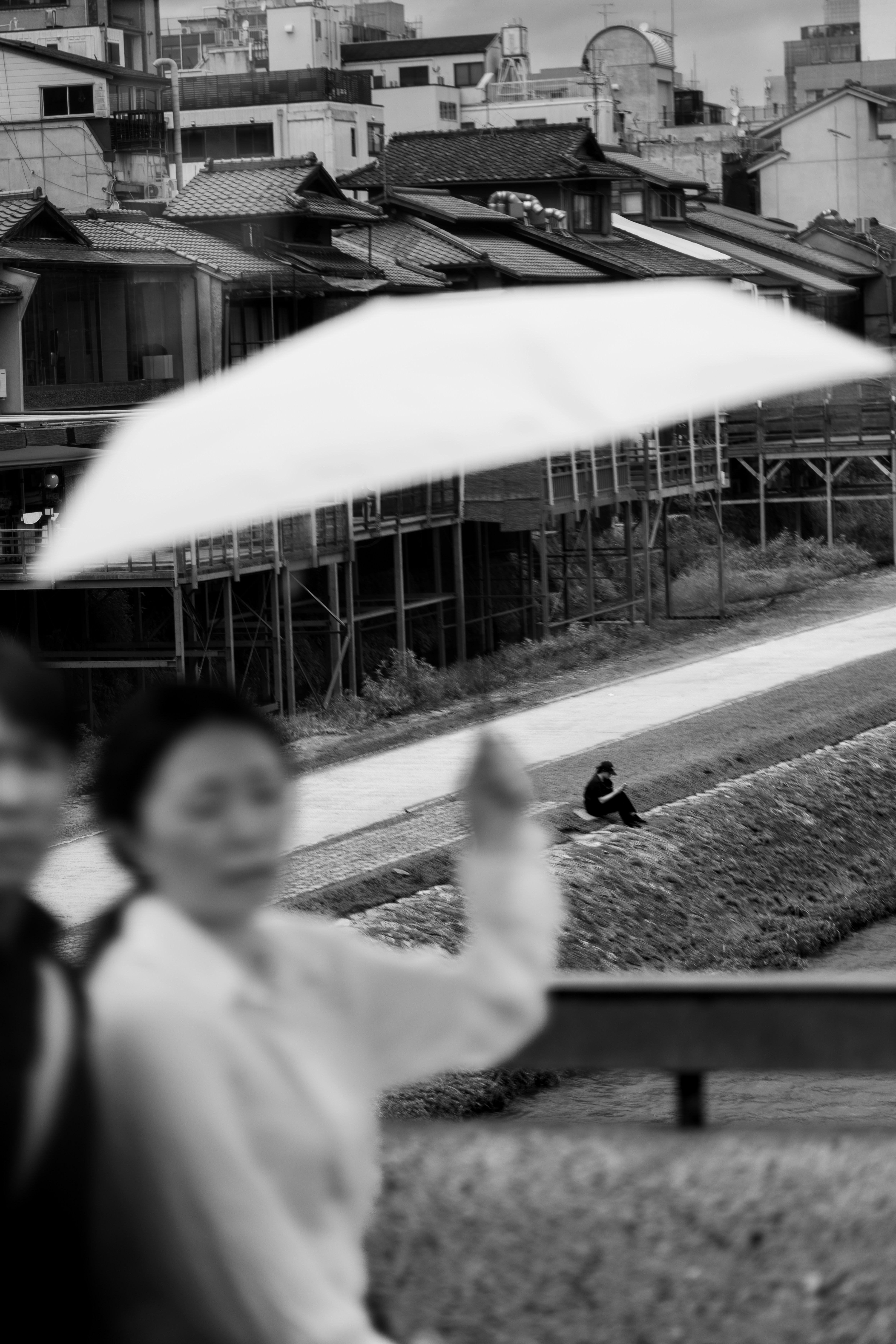 Woman holding umbrella with blurred figures in foreground