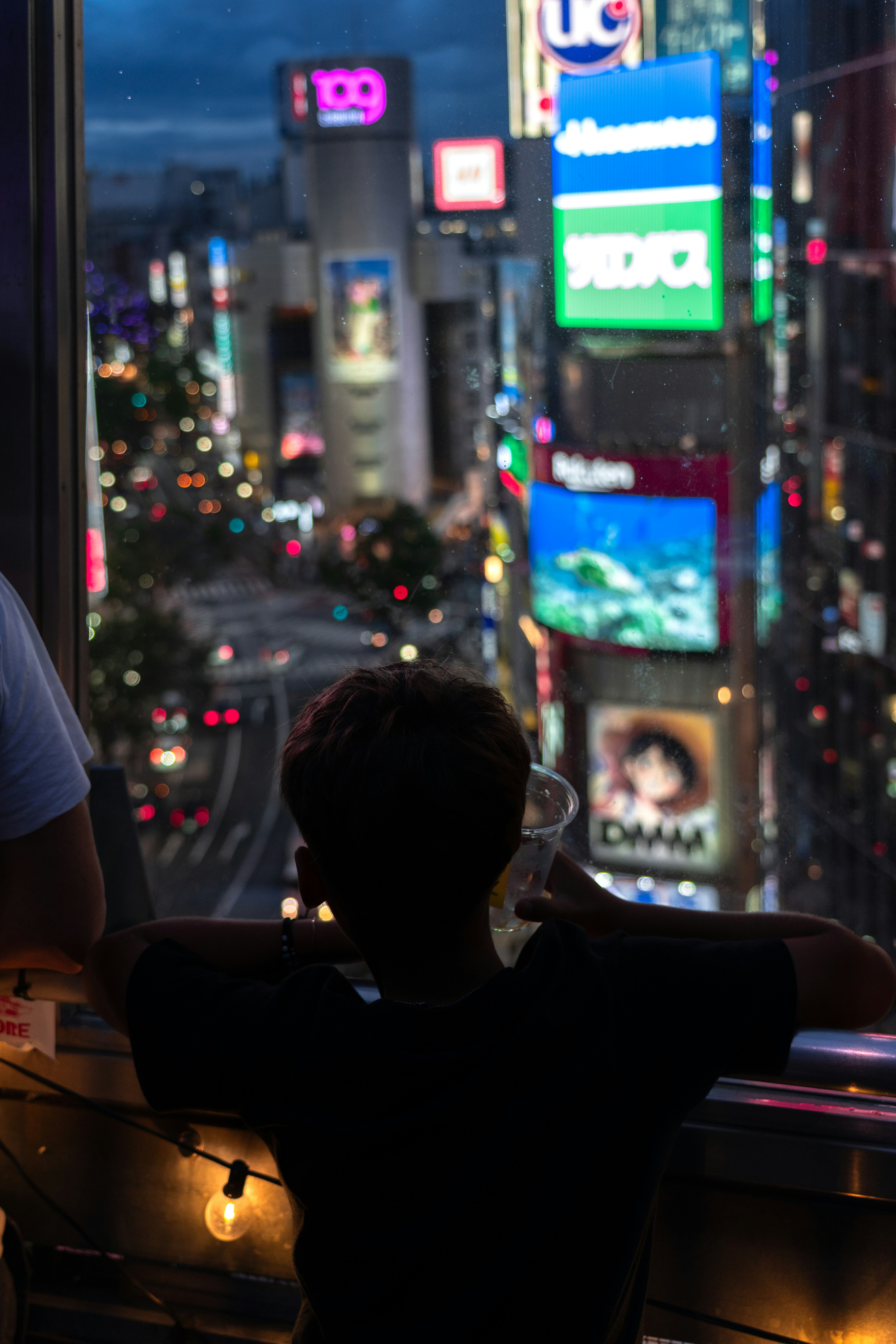 Person looks out at a vibrant city skyline at night.