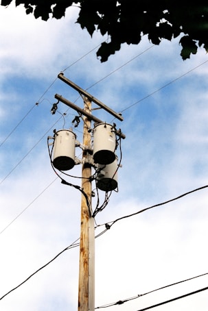 Utility pole with transformers and wires against sky.