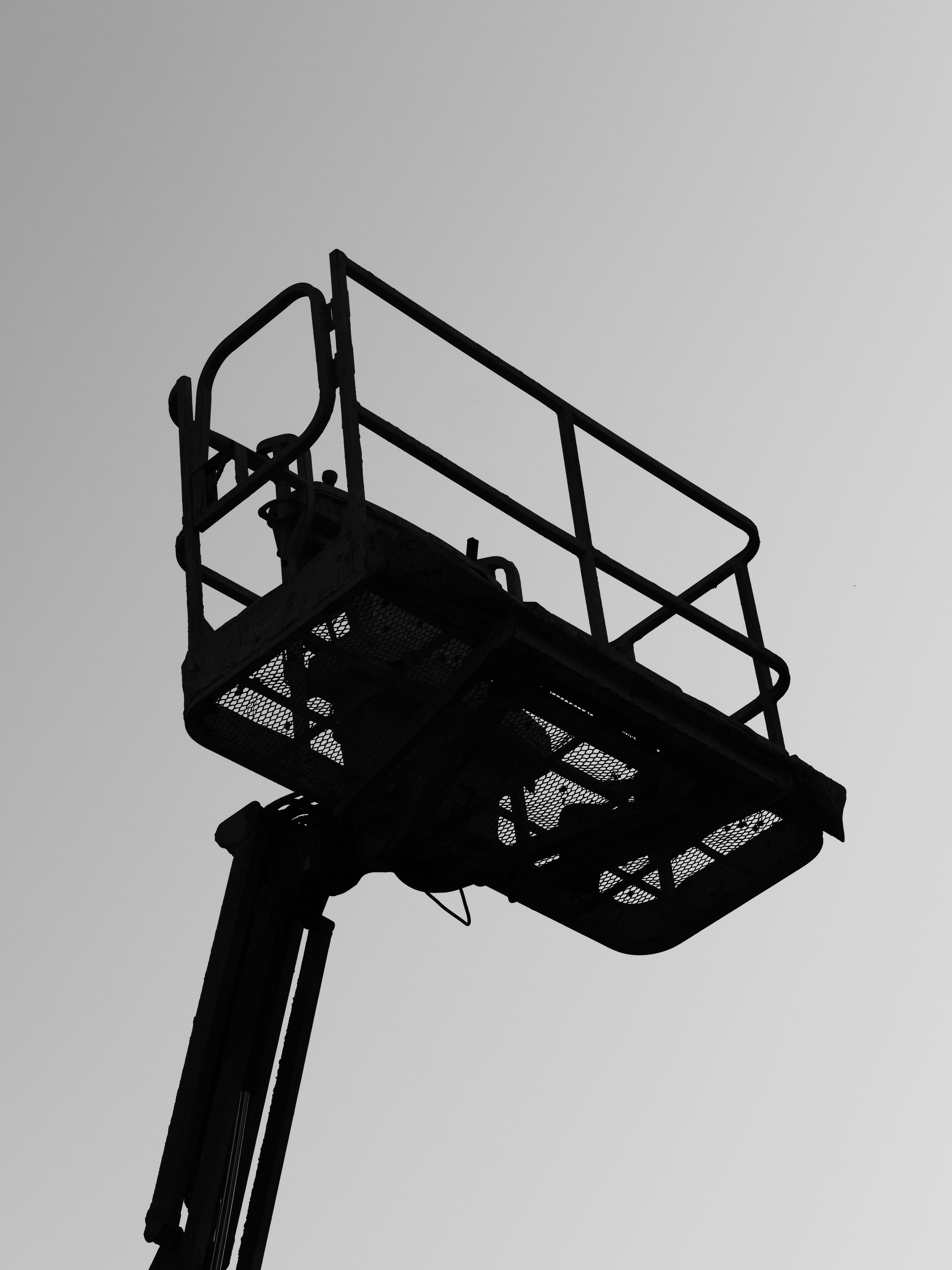 Silhouette of a cherry picker lift against sky