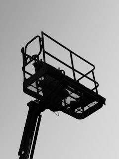 Silhouette of a cherry picker lift against sky