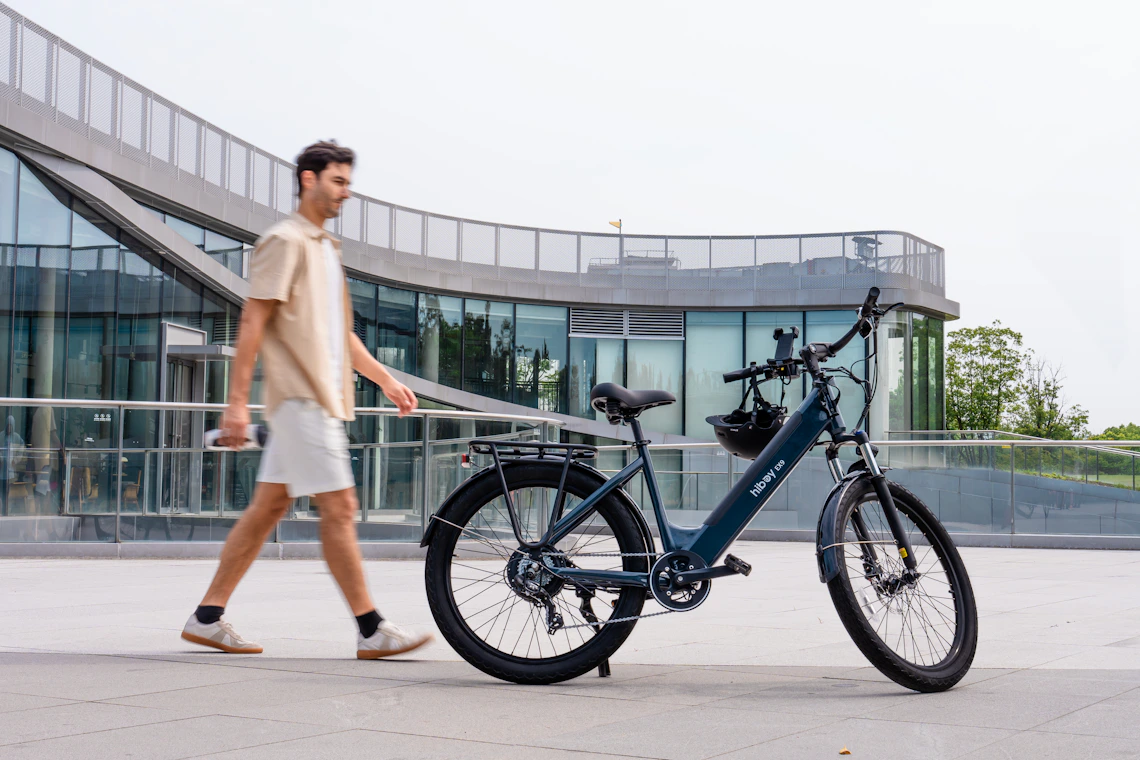 Urban cyclist walking with an electric bicycle beside modern architecture