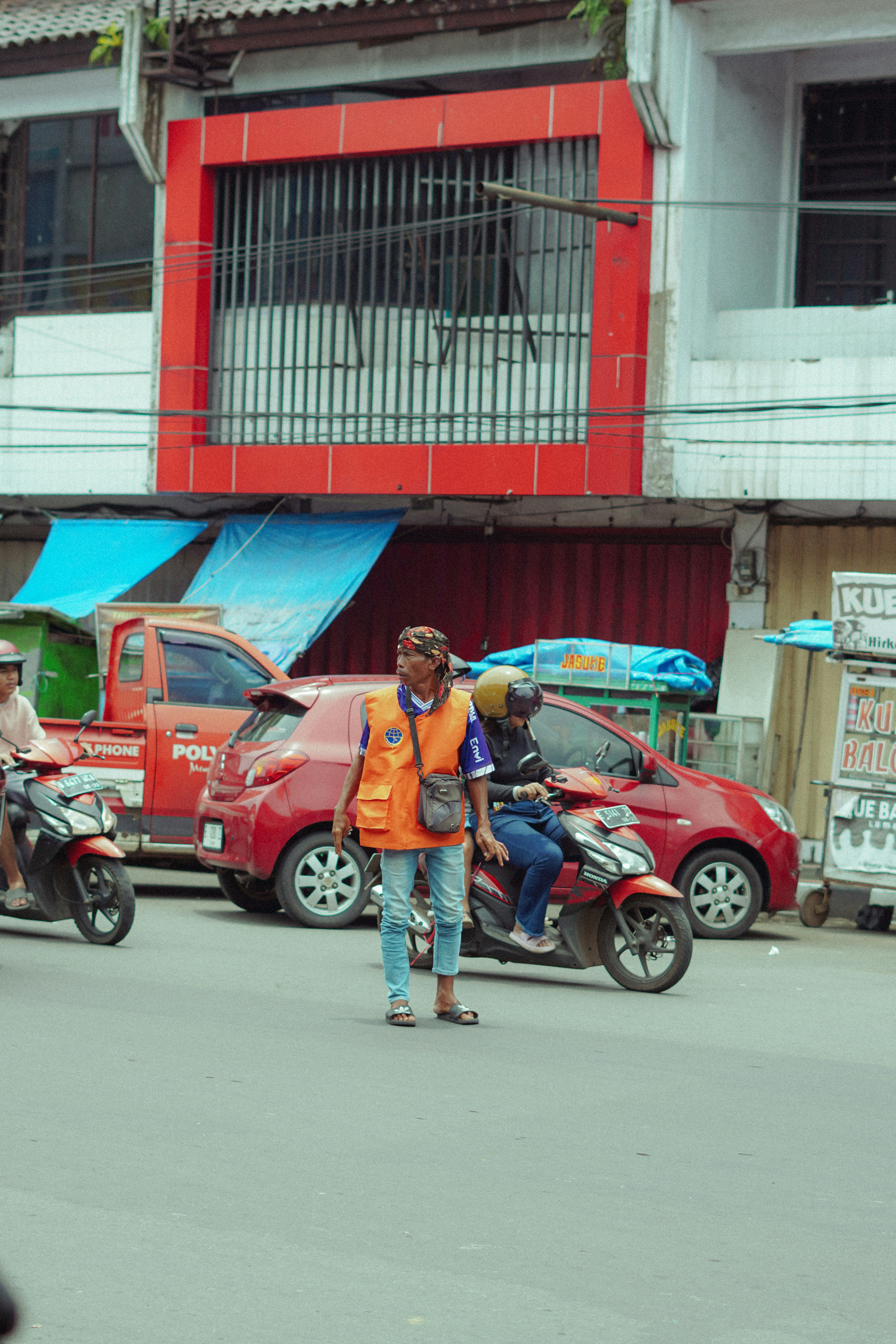 Pria berrompi oranye mengarahkan lalu lintas di jalan.