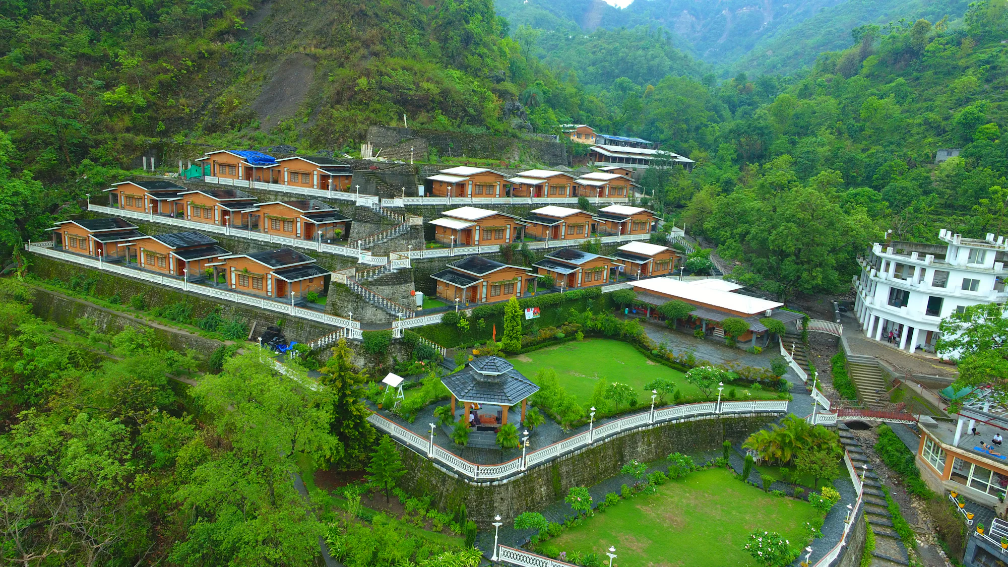 Aerial view of the villas stepped down a green mountainside around landscaped lawns