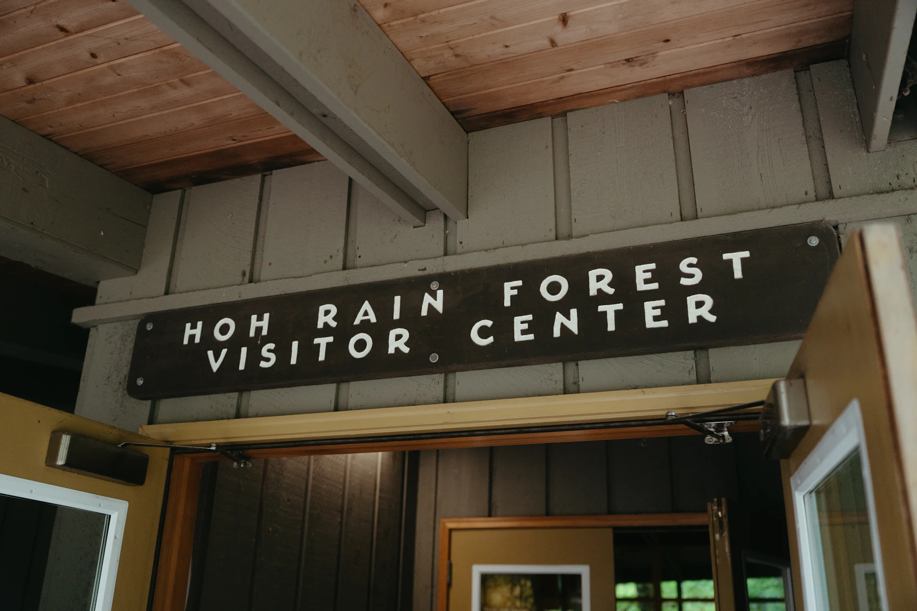 A routed wooden sign reading Hoh Rain Forest Visitor Center above an open doorway